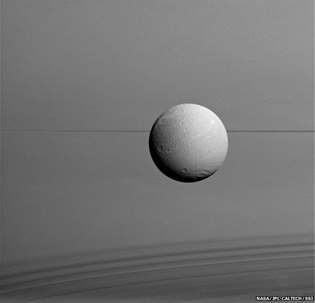  dione hangs in front of Saturn and its icy rings in this view, captured during Cassini's final close flyby of the icy moon 
